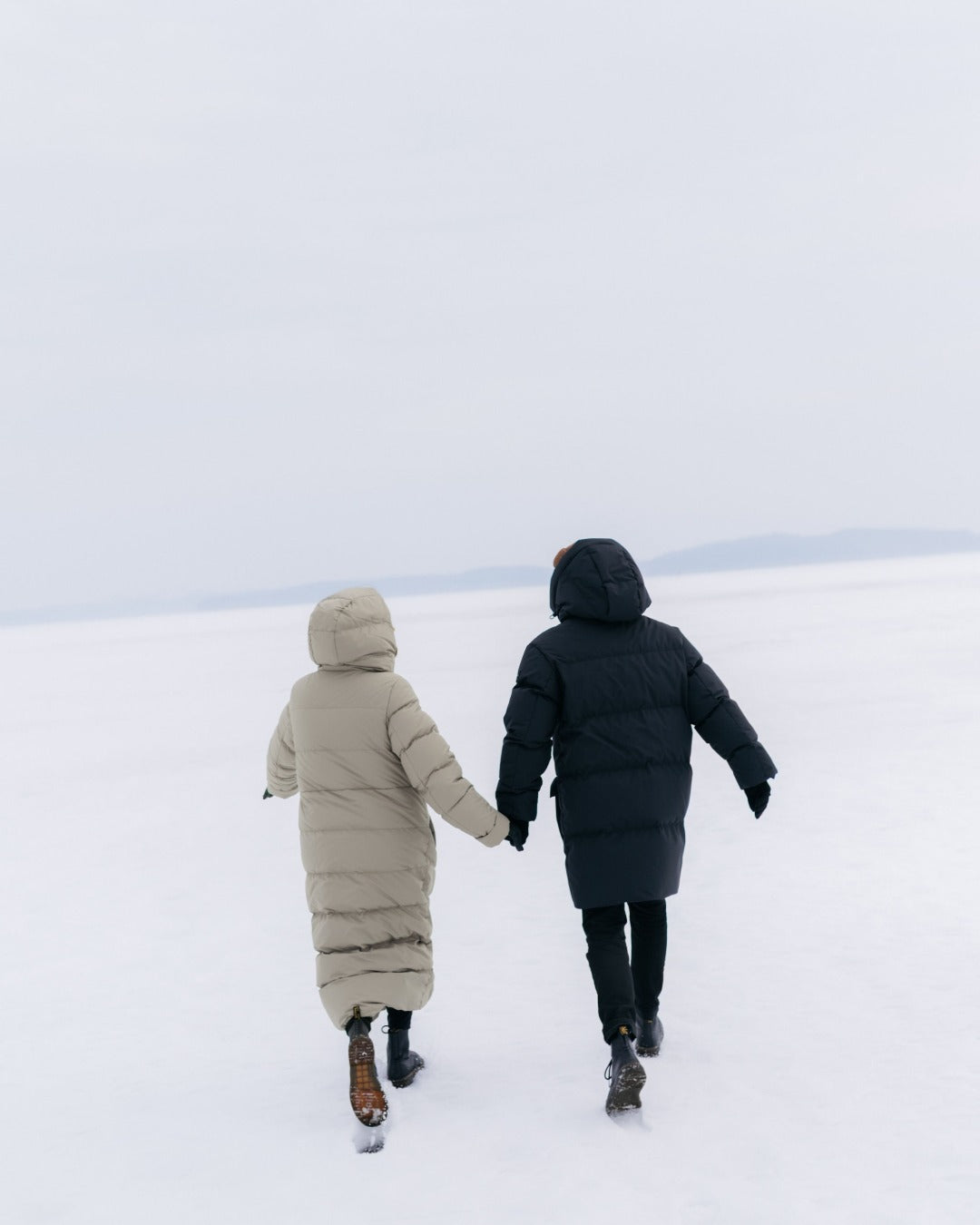 Two people walking hand in hand on a snowy landscape