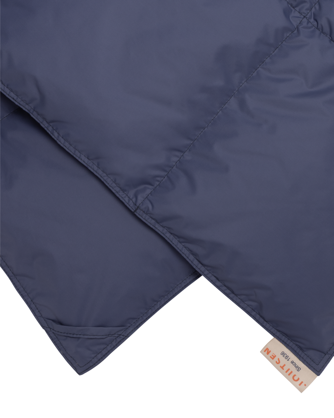 Close-up of a blue quilted blanket with a brand label