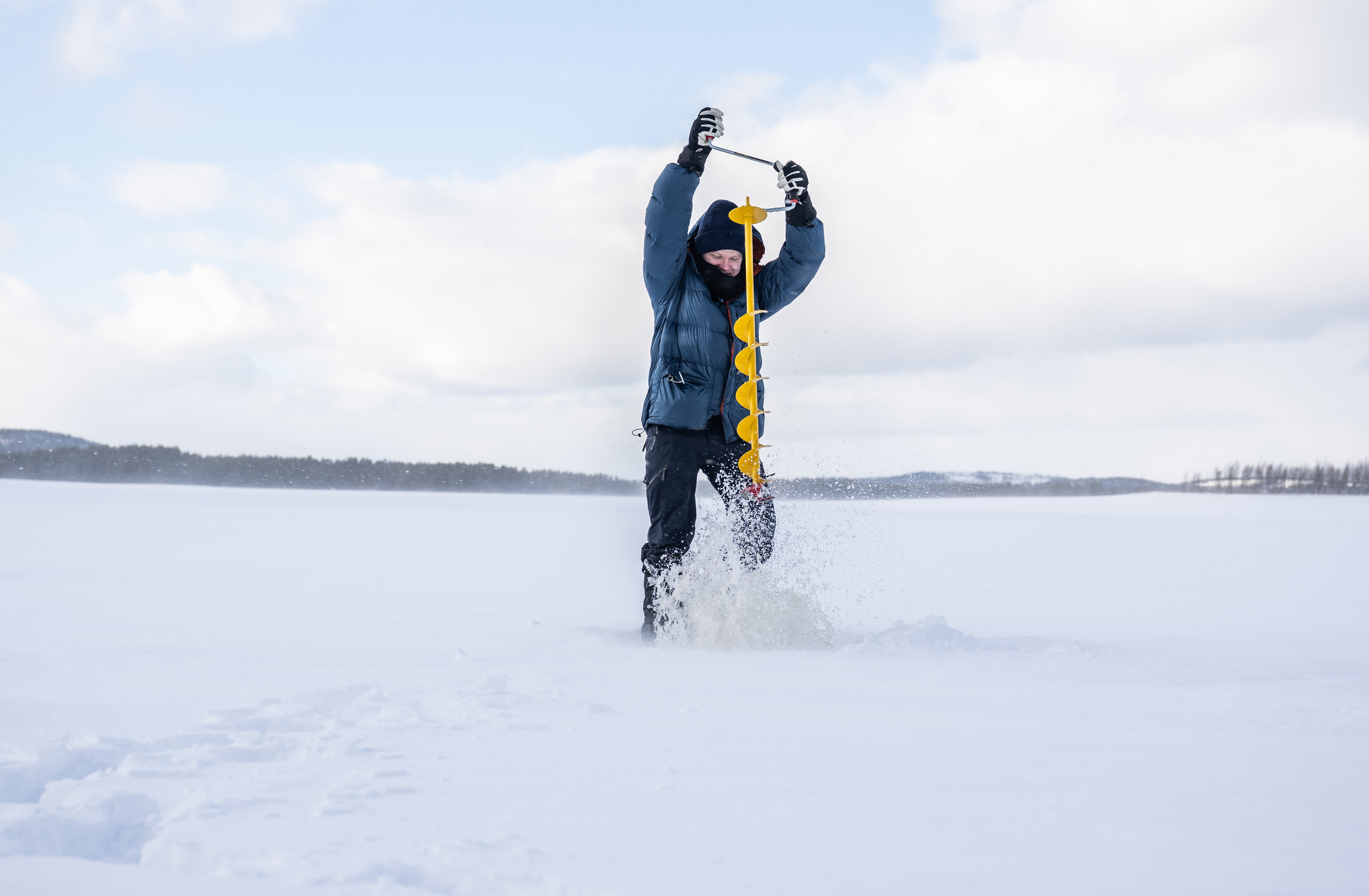 Person ice fishing on a frozen lake with a fishing pole