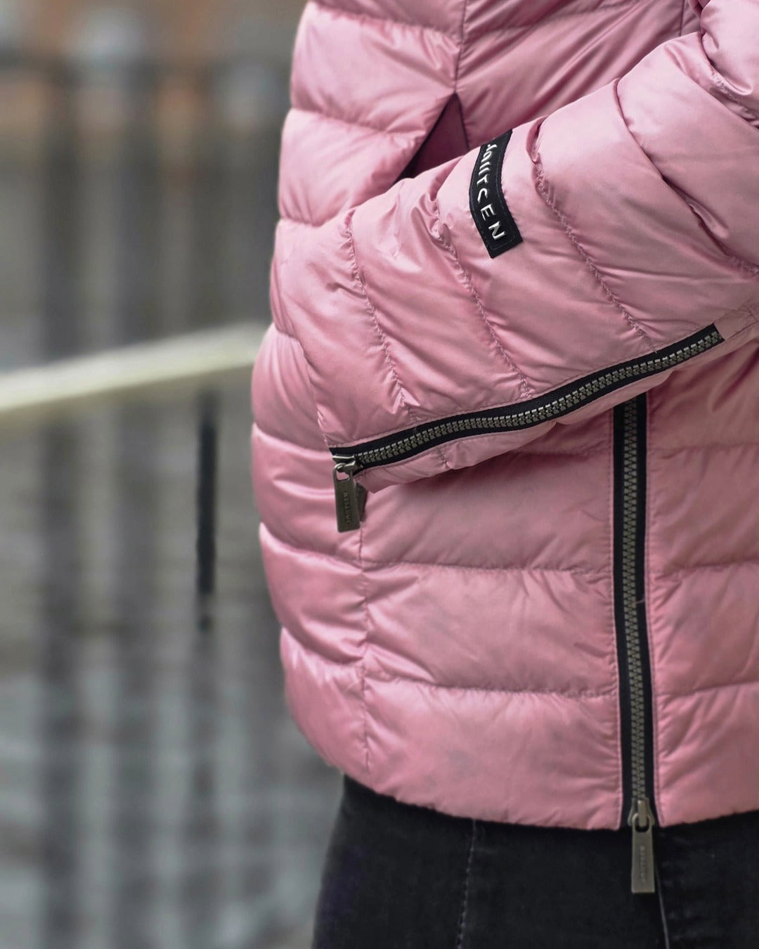 A close-up of the zippered slits at the cuff and side seam of the pink Maana light down coat (color: Wildflower).