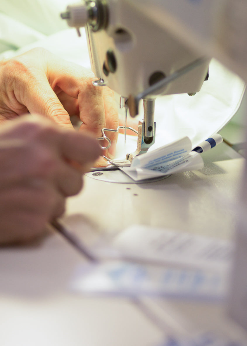 Close-up of a sewing machine with a person's hands operating it.