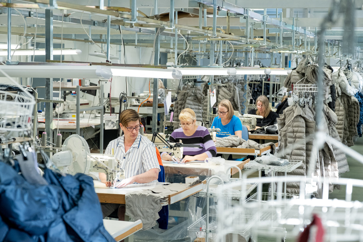 Factory interior with workers at their stations, surrounded by machinery and materials.