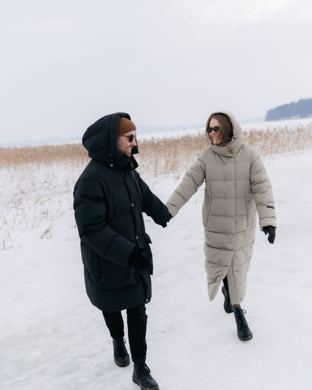 Two people walking hand in hand on a snowy field