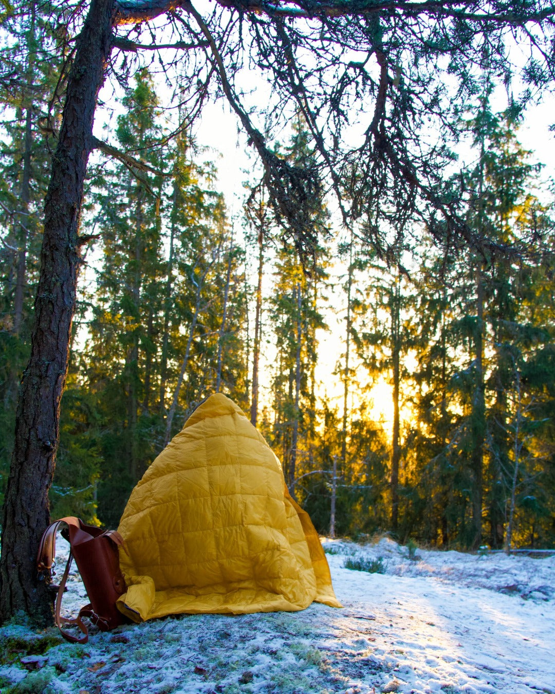 Yellow Kulkuri down blanketon a persons shouldes in a forest with sunlight filtering through the trees