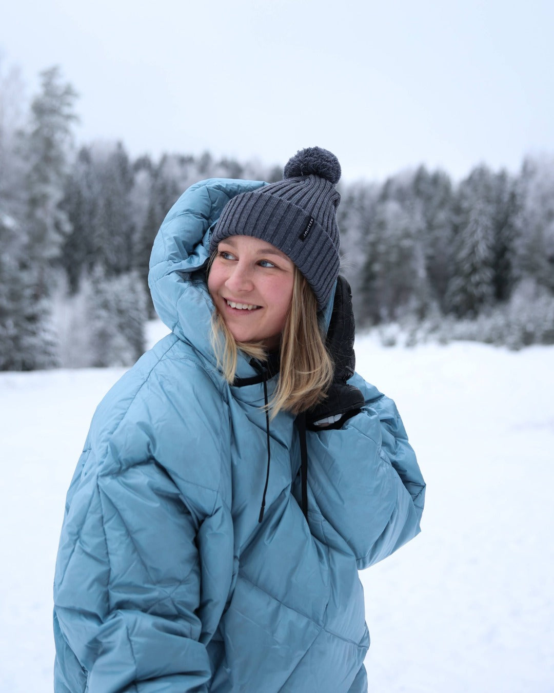 Person wearing a down anorak and gray beanie in a snowy landscape