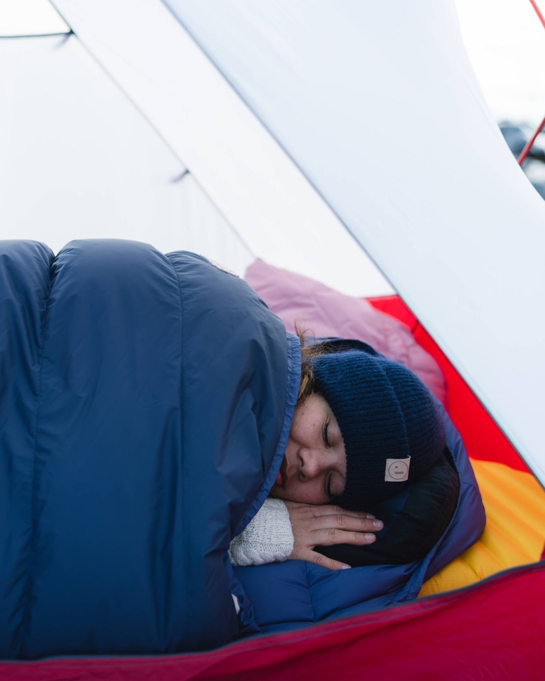 Person sleeping in a blue sleeping bag inside a tent.