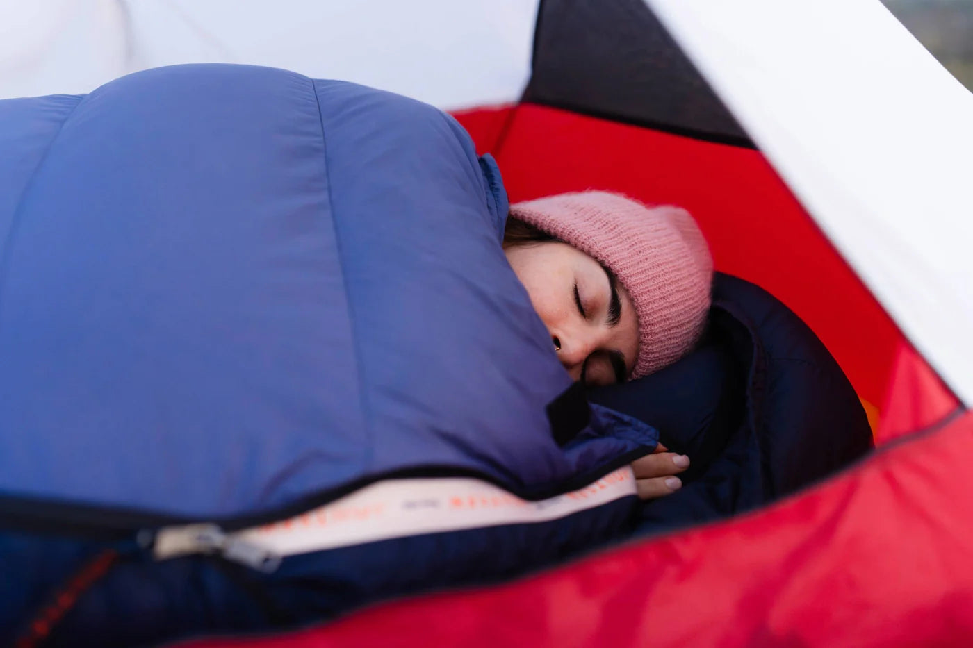 Person sleeping in a blue sleeping bag inside a tent