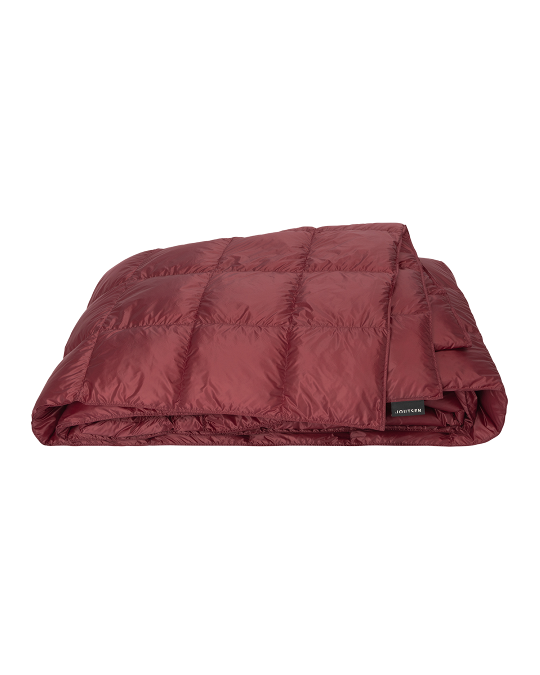 The red Henkäys bedspread is neatly folded, and its surface is decorated with stitched square quilting patterns.